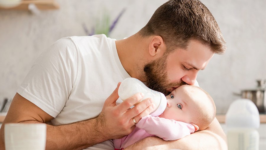 Vater, der sich fragt, wie lange er seinem Baby die Flasche geben soll.