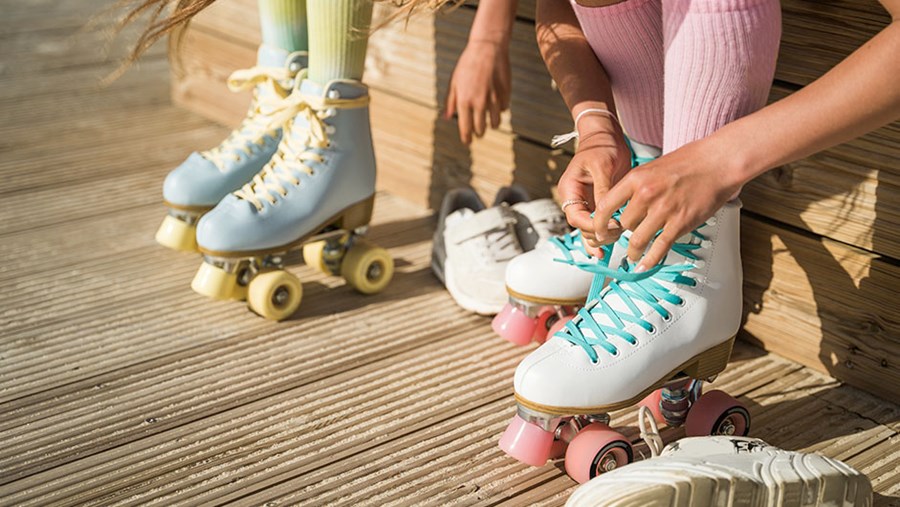 Zwei Frauen binden sich ihre schönen, bunten Rollschuhe.