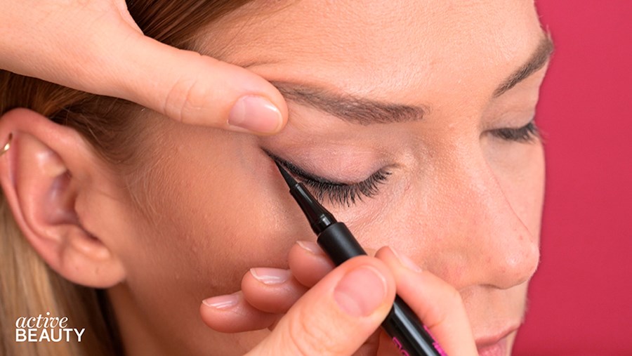 schwarzem Eyeliner einen schmalen Cat-Eye-Lidstrich ziehen