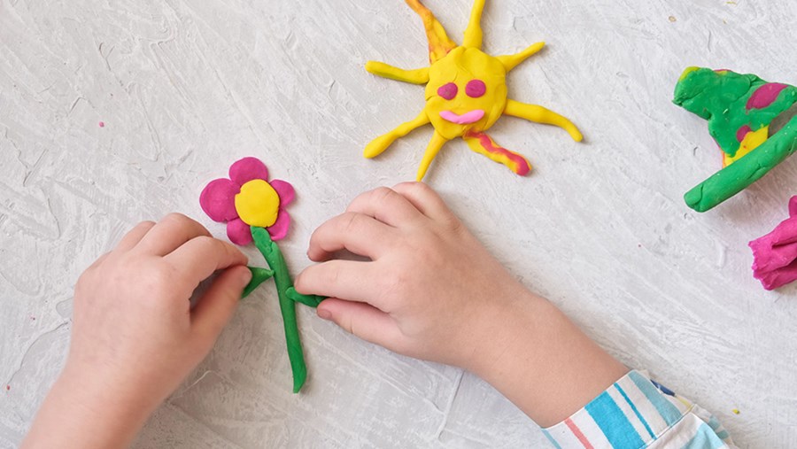 Kinderhände formen eine Blume aus Knete