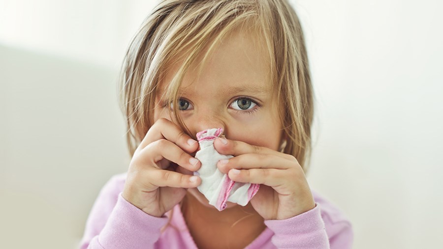 Hausstaubmilbenallergie bei Kindern: kleines Mädchen schnäuzt sich