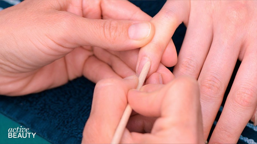 Die Nagelhaut wird mit einem Stäbchen zurückgeschoben